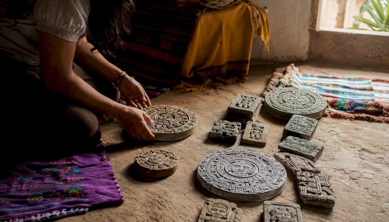 Hands tracing Mayan calendar glyphs on stones