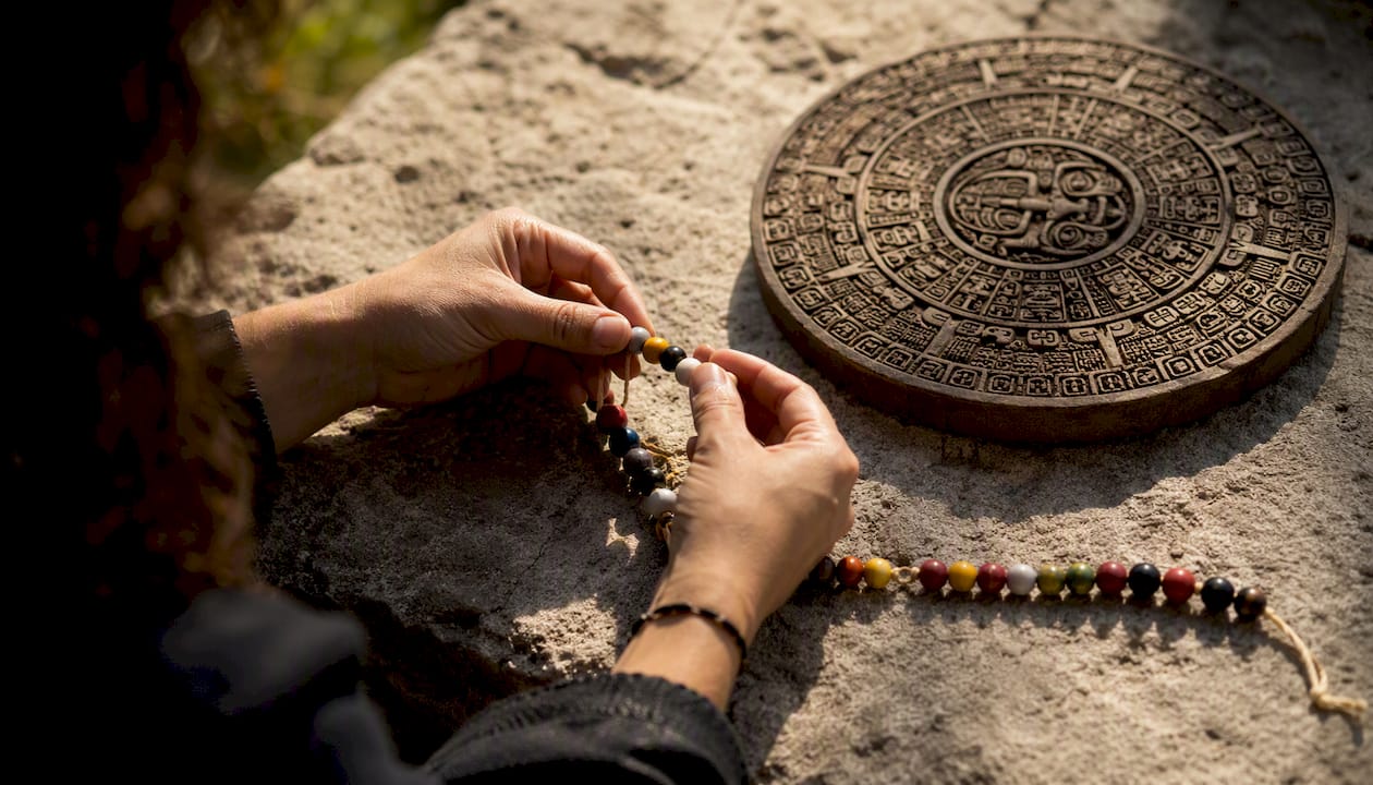 Hands calculating Mayan date using beads and calendar disk