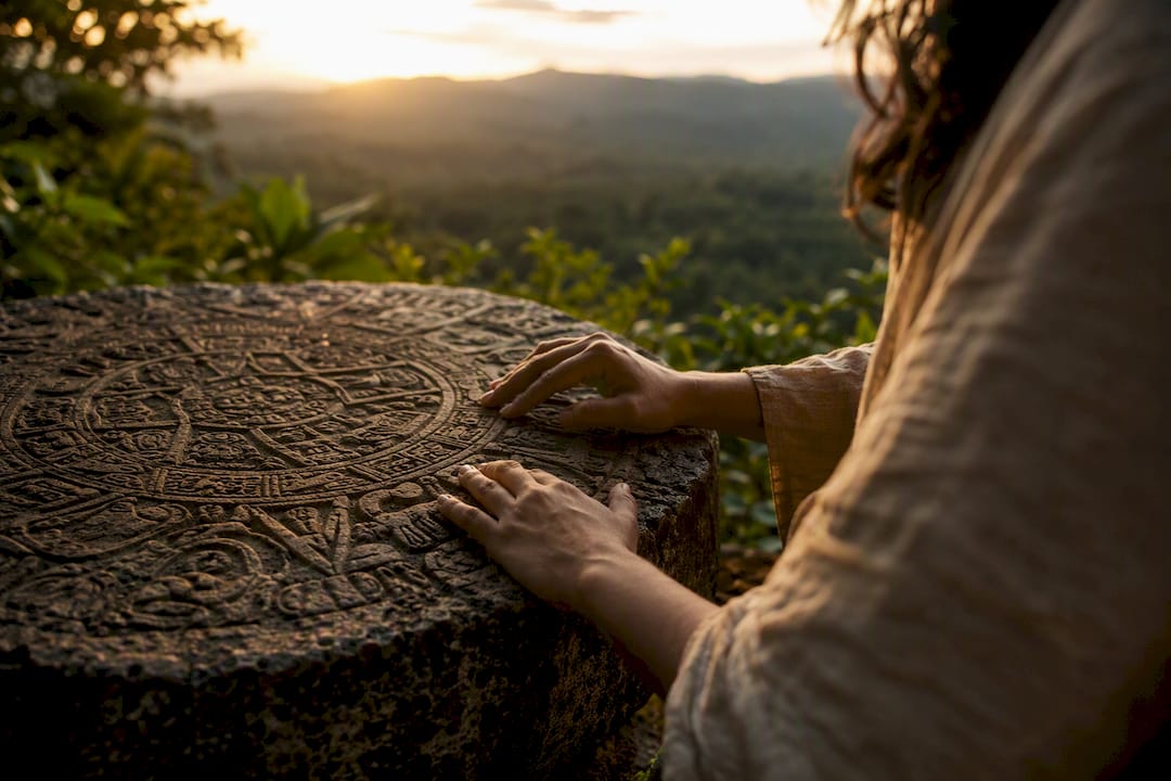 Hands tracing Mayan calendar glyph carvings
