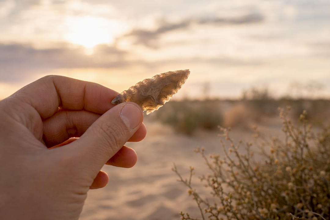 Hand holding a small sharp flint blade outdoors